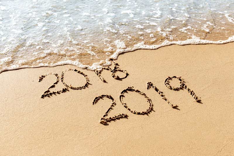sandy beach with 2018 and 2019 written in the sand